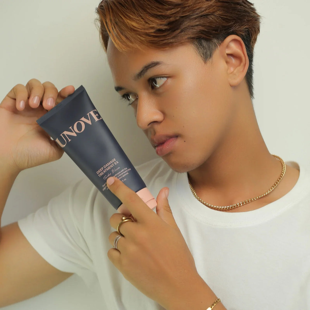 UNOVE Deep Damage Treatment EX hair mask for repair and softness, held by person with styled hair