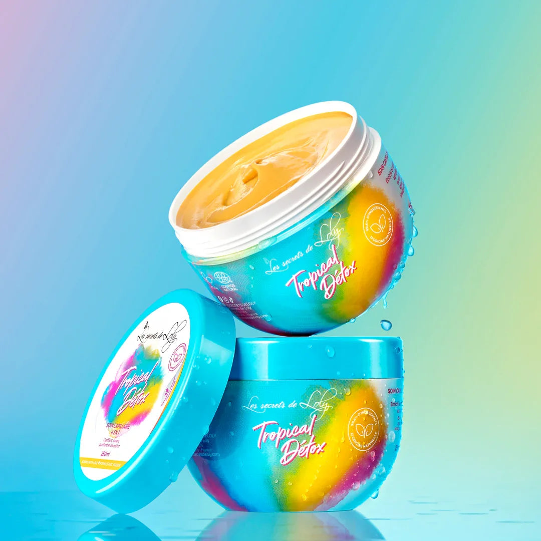Two colorful Tropical Detox hair mask containers stacked on a blue gradient background