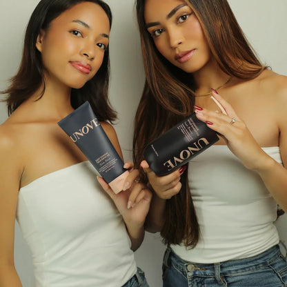 Two women in white tops holding Unove hair care products against a neutral background
