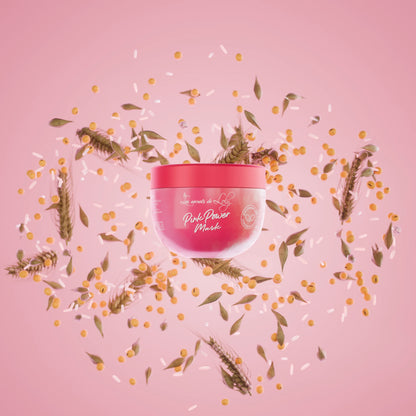 Pink Power Mask hair treatment jar with grains, leaves, and seeds on a pink background