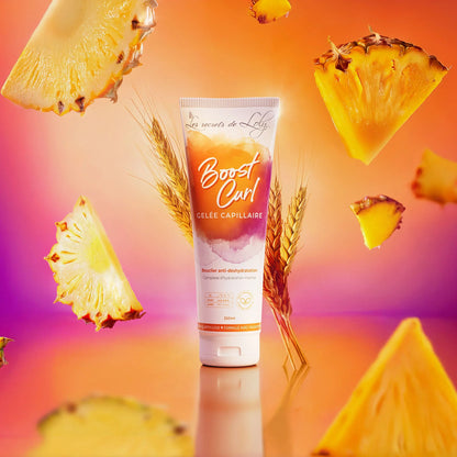 Boost Curl hair gel tube with wheat stalks and pineapple slices on an orange background