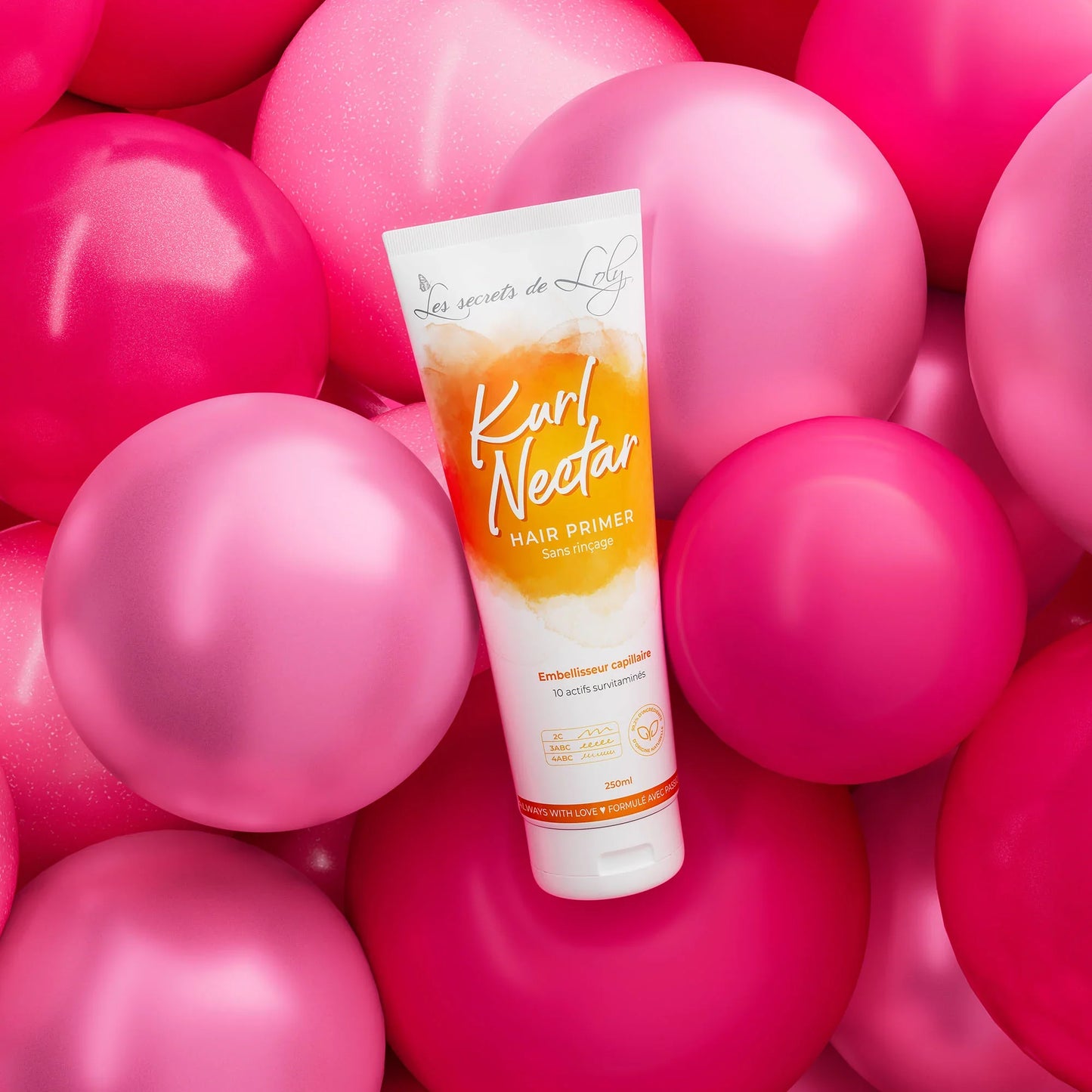Hair primer tube surrounded by pink balloons, haircare product for curly hair