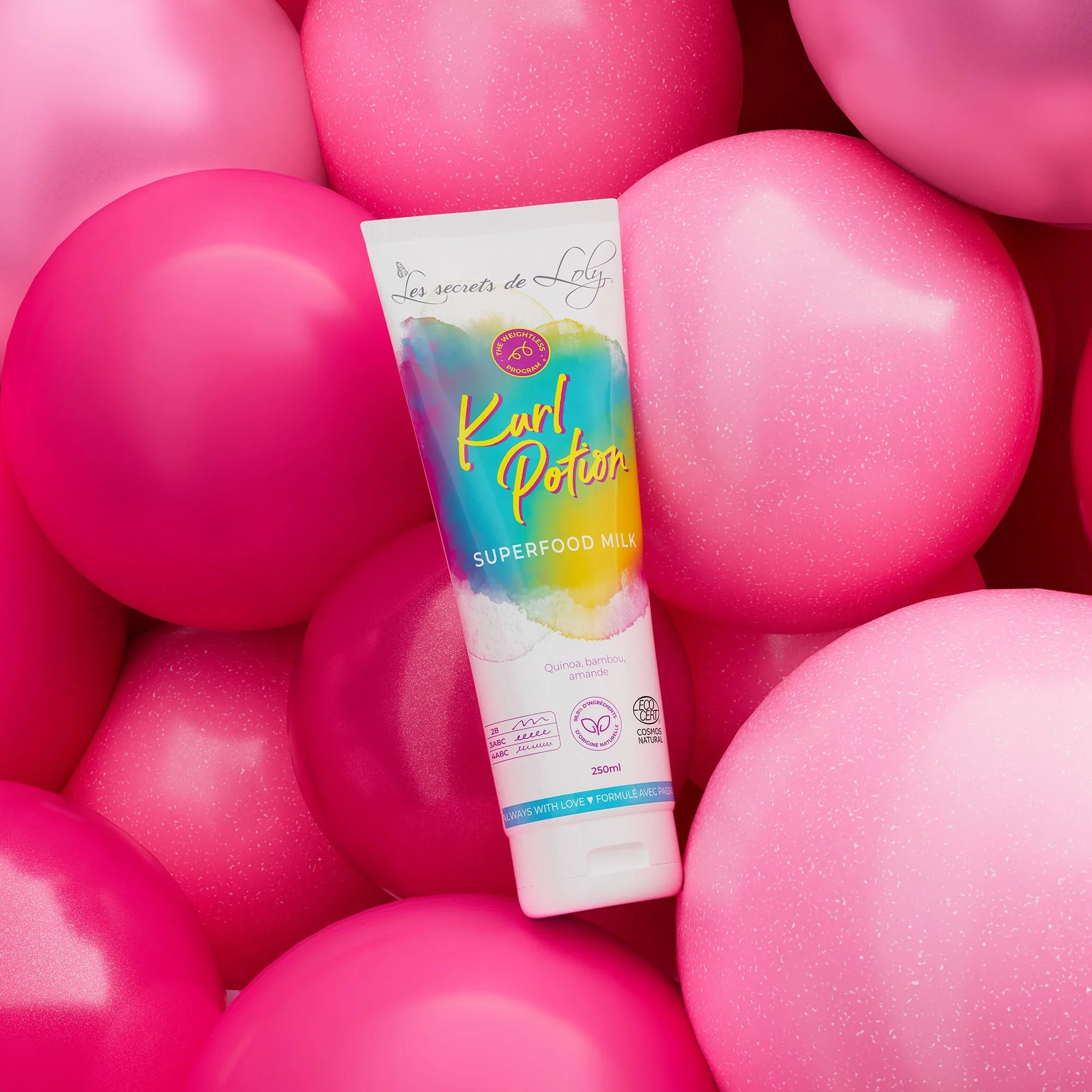 Kurl Potion superfood milk hair product tube surrounded by pink balloons