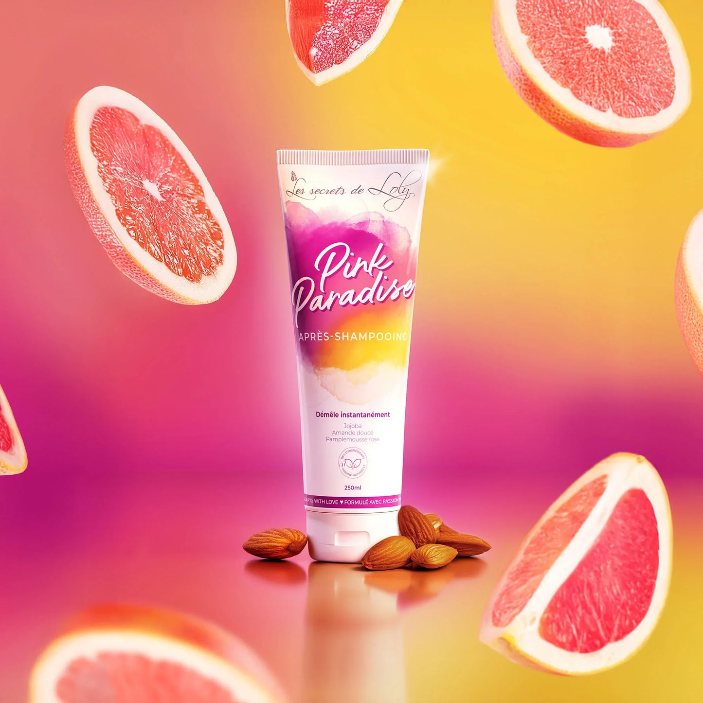 Pink Paradise hair conditioner tube with grapefruits and almonds on a pink and yellow background
