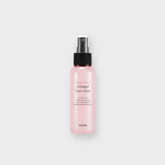 Pink bottle of raspberry vinegar hair mist with black spray cap on white background.
