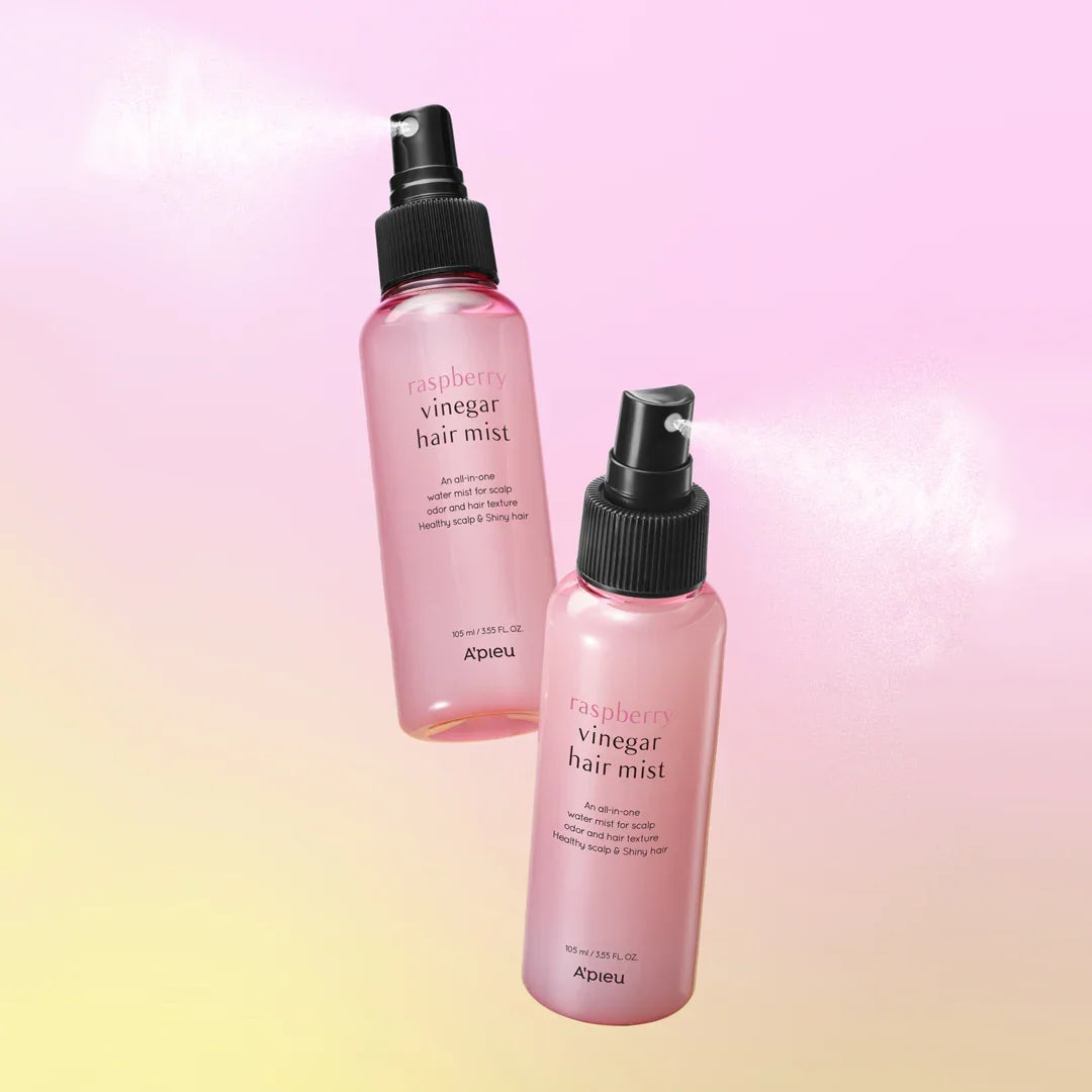 Two pink bottles of raspberry vinegar hair mist on a pastel background, spraying fine mist